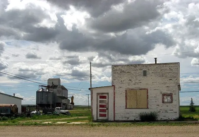 Old building and grain elevator under stormy sky